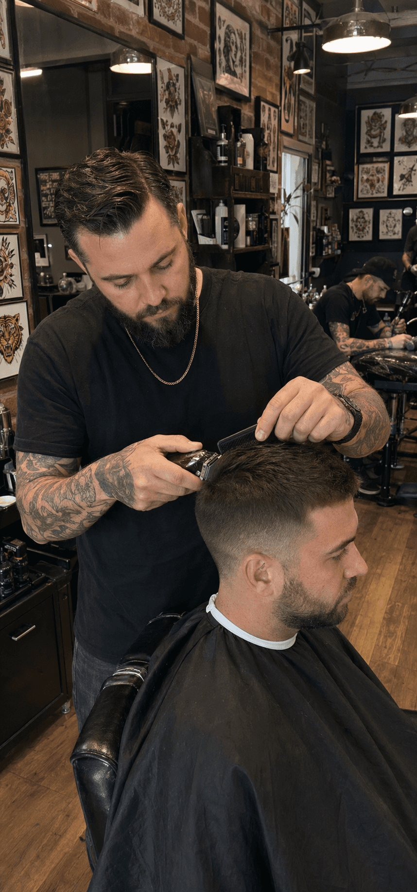 Tattoo artist working with a client inside a busy barber and tattoo studio