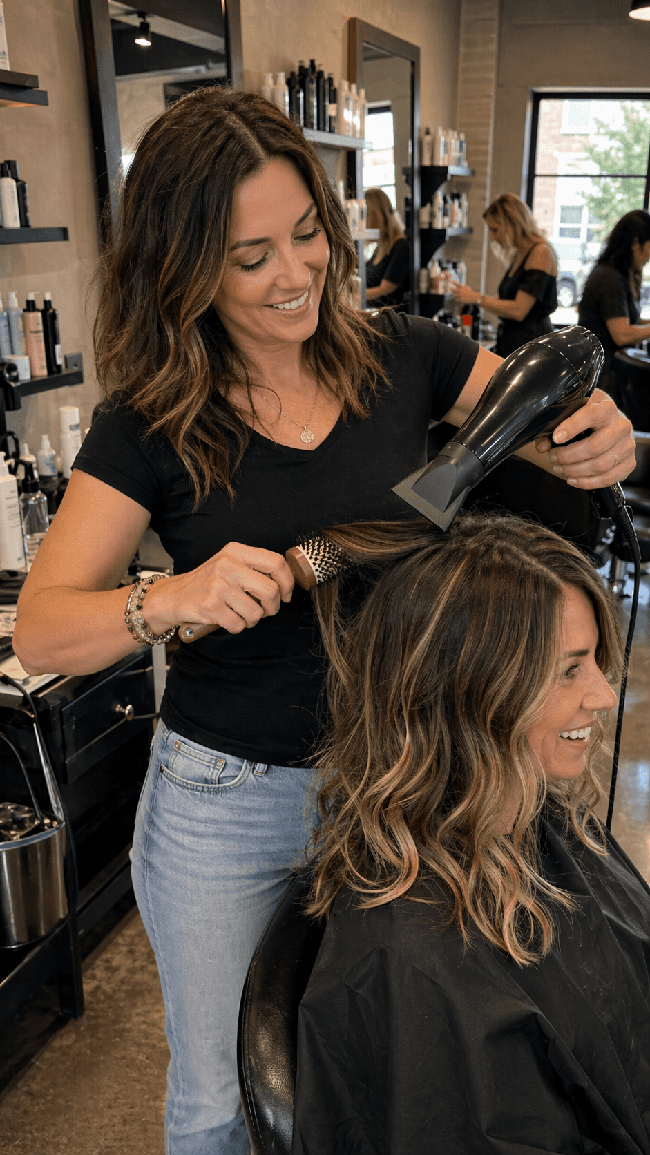 Female salon owner smiling while styling a client's hair in a bright modern salon